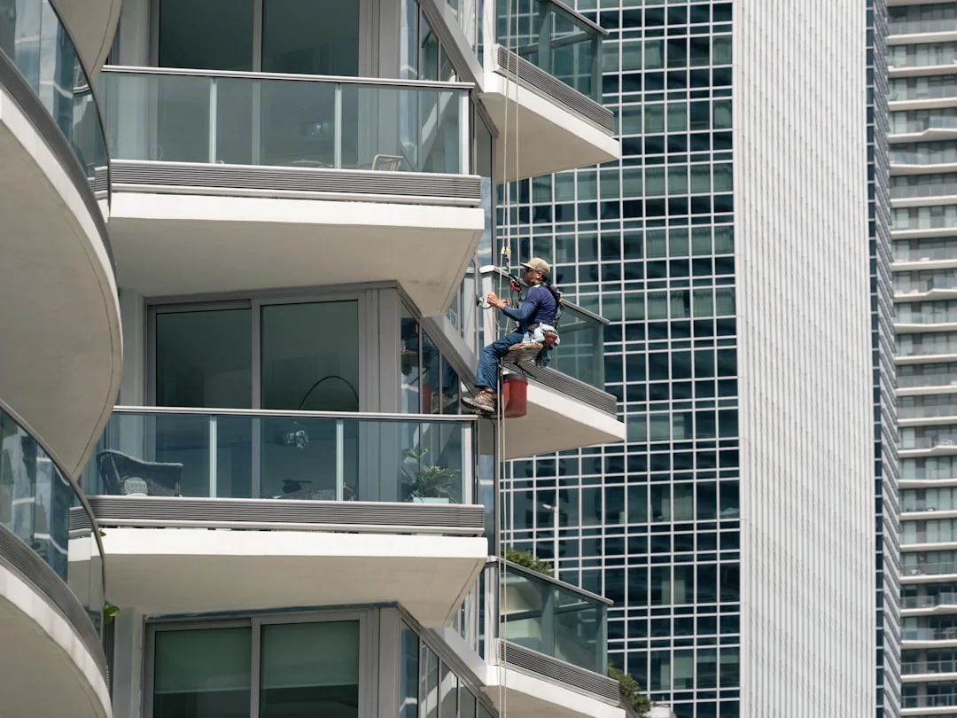 High-rise window washers in safety gear cleaning a skyscraper facade.